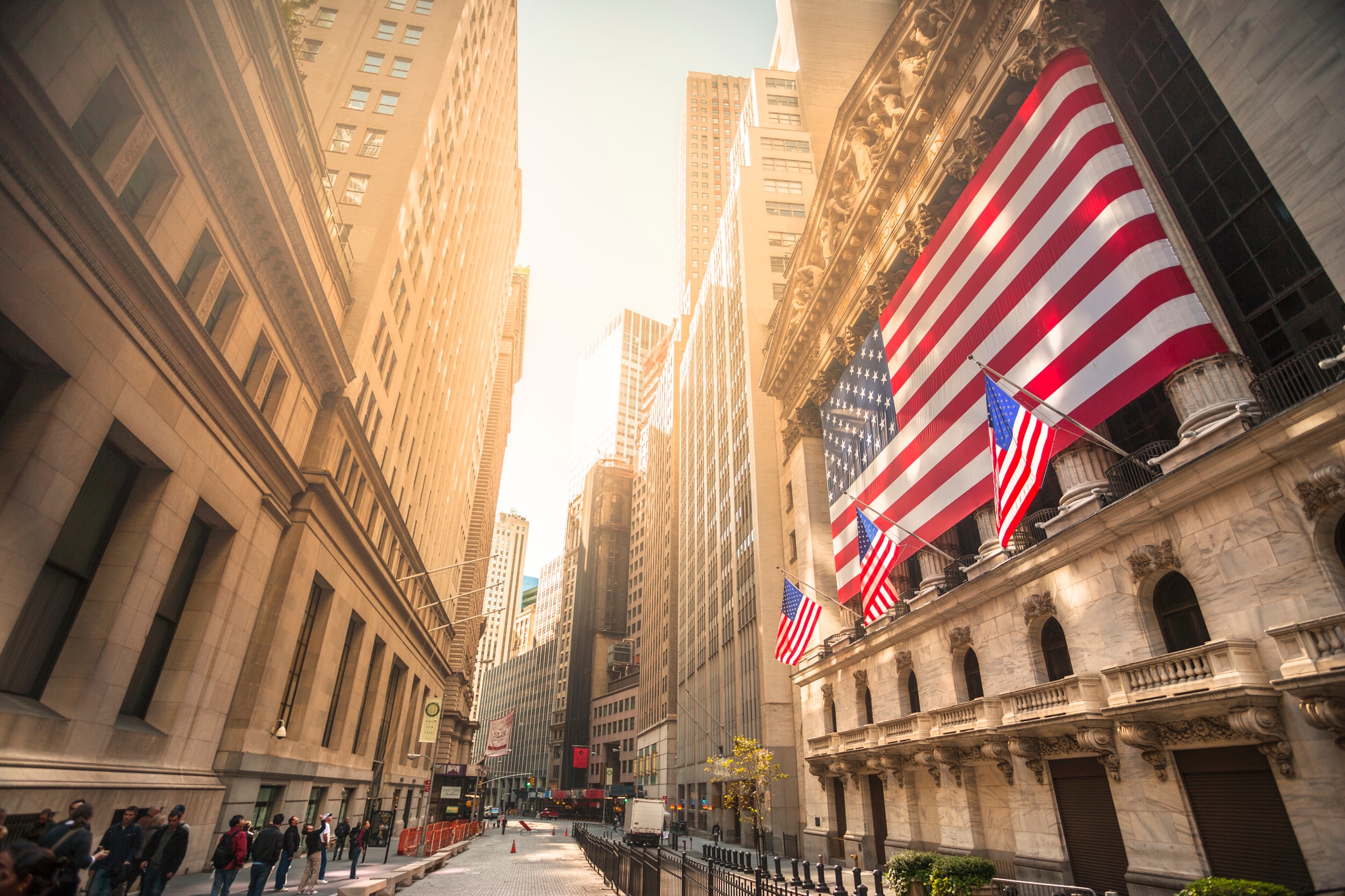 A sunny Wall Street with US flags